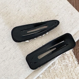 Detailed back view of luxury black metal hair clips with smooth finish and rivets