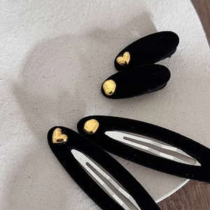 Detail view of black velvet hair clips with gold heart and pebble metal embellishments