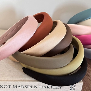 Minimalist thick sponge padded headband in various matte fabric colors on art book