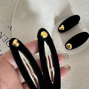 Detail of vintage black velvet hair clips with gold heart and geometric metal buckles