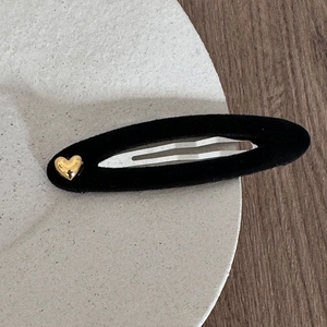 Detailed macro view of black velvet BB hair clip with elegant golden heart metal decoration