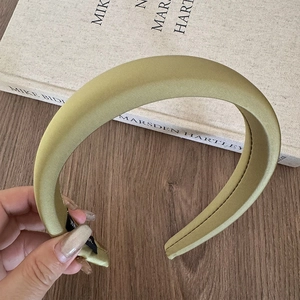 Close-up of padded sponge headband in olive green satin fabric with smooth texture