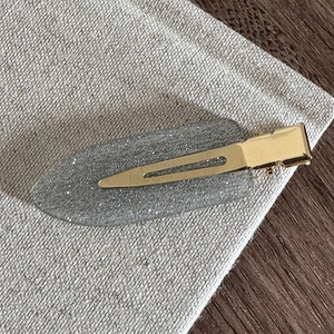 Gros plan d'une barrette à cheveux ovale grise scintillante avec paillettes argentées