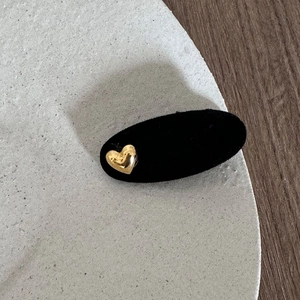 Detail of vintage black flocked hair clip with a small gold heart metal accent