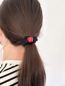 Close-up of a red bead on a black scrunchie worn on a ponytail for daily hair styling
