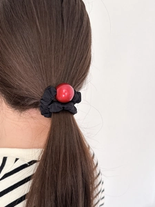 Elastic black hair tie with a large glossy red bead on a ponytail hairstyle