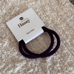 Dettaglio di due elastici per capelli in velluto viola su scheda fatta a mano
