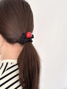 Elastic red ball hair tie with black fabric scrunchie on brown hair with striped shirt