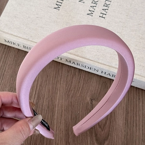 Detail showing smooth light pink satin fabric and sponge padding on the headband