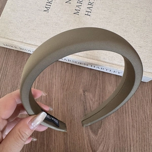 Detail of a thick padded olive fabric headband with a black Hand Made woven label
