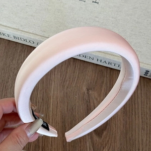Detail of light pink padded headband with satin texture on a wooden table setup