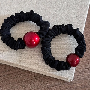 Close-up of red high-gloss beads on elastic black pleated scrunchies for hair styling