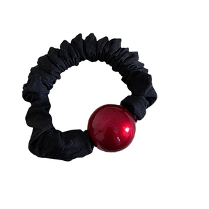 Elegant black scrunchie with red resin bead accent on a white background