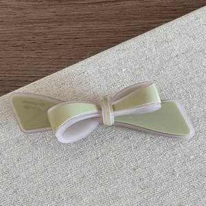 Détail de la barrette à nœud en acétate faite main en vert clair et violet sur lin