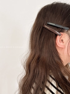 Detail of elegant black and dark brown handmade hair clips on brunette wavy hair