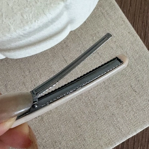 Macro shot of an open vintage hair clip showing the metallic teeth and beige glossy finish