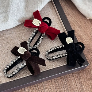 Velvet bow hair clips with rhinestones in red, brown, and black colors on wooden tray