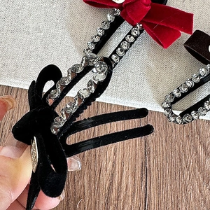 Close-up of velvet bow hair clips with rhinestone edges and golden leaf accents