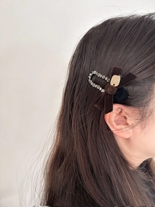 Close-up of velvet bow hair clip with sparkling rhinestones and a gold metal plate