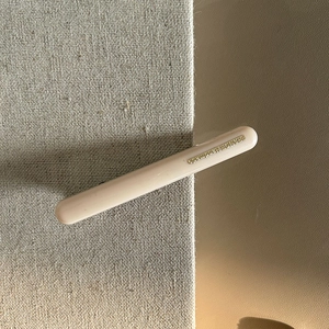 Dettaglio di un fermaglio per capelli in resina beige con scritta dorata HBAIKA handmade