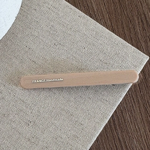 Detail of matte beige hair clip with gold France Handmade lettering on linen texture