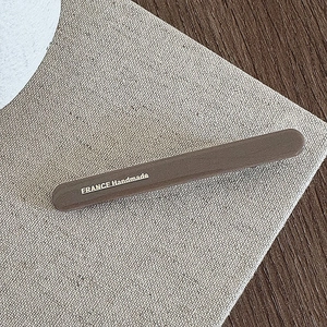 Close-up of a brown handmade hair clip with silver France lettering on a textured surface