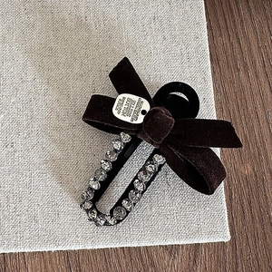 Detail of brown velvet bow hair clip with rhinestone U-shaped metal and logo plate