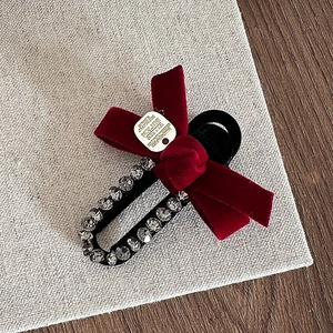 Detailed shot of a red velvet bow hair clip with sparkling rhinestones and metal label