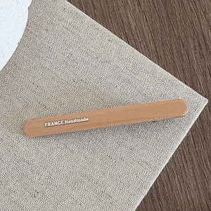 Detailed close-up of matte brown hair clip with golden France Handmade engraving