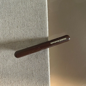 Dettaglio del fermaglio marrone scuro lucido con scritta dorata France Handmade
