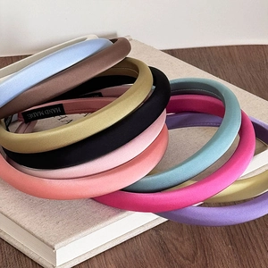 Padded satin silk headbands in various colors stacked on a vintage aesthetic book