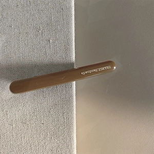 Dettaglio della molletta in acetato marrone con incisione France Handmade su sfondo in tessuto
