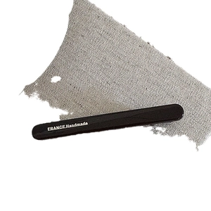 Minimalist black hair clip with white FRANCE Handmade text on grey linen background