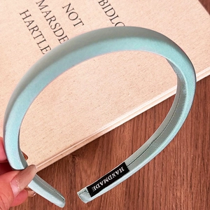 Detail of mint green padded headband with silk satin texture and handmade label