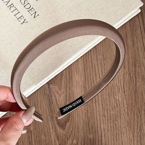 Detail of coffee brown satin sponge headband with a handmade label on wooden background