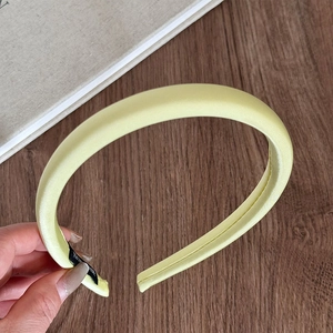 Detail of light yellow satin padded headband showing smooth fabric and fine stitching