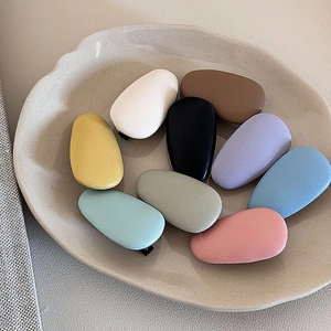 Minimalist teardrop leather hair clips in assorted matte pastel colors on a ceramic tray