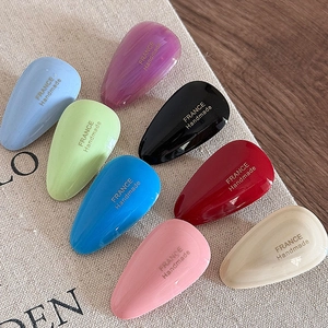 Detailed macro view of colorful acetate teardrop hair clips with gold label inscriptions
