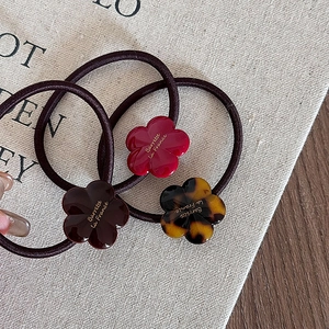 Détail d'élastiques à fleurs avec lettrage doré en rouge, marron et motif écaille de tortue