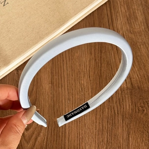 Close-up of light blue satin headband with handmade label on wooden background