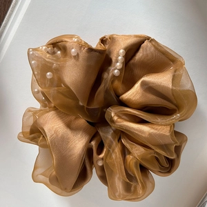Detailed close-up of champagne organza hair scrunchie with white pearl accents
