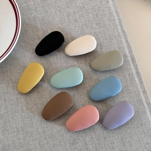Detailed top view of nine matte teardrop hair clips in Morandi colors on linen background