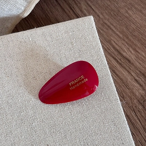 Macro view of dark red teardrop acetate hair clip with gold France Handmade lettering