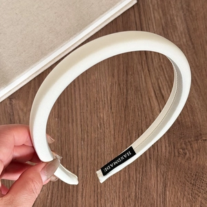 Close-up of a handmade white satin sponge headband with a high-quality silk texture