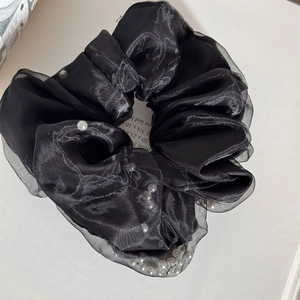Close-up of black mesh scrunchie with layered organza fabric and white pearl accents