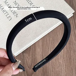 Detailed macro view showing the 1cm top width and handmade label of the black fabric headband