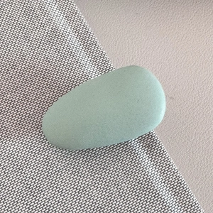 Close-up of a mint green matte pebble-shaped hair clip with smooth elegant texture