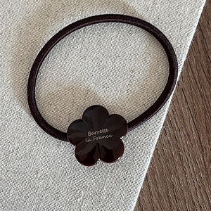 Détail de l'élastique à cheveux fleur avec gravure Barrette La France sur acétate marron