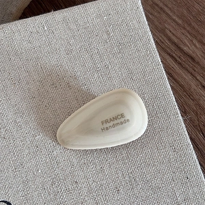 Macro view of teardrop acetate hair clip with gold France Handmade engraved text on linen