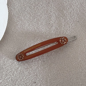 Detail van amberkleurige hars haarclip met champagne kristallen en gouden tekst